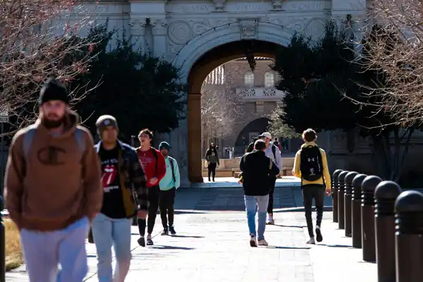 Students walking through a university campus archway. Photo by Brelyn Bashrum on Unsplash