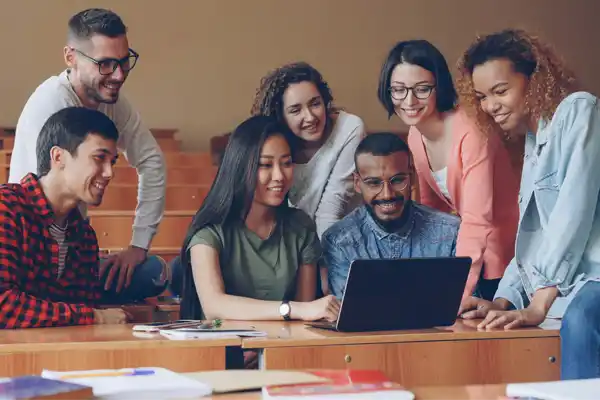 Diverse group of students collaborating around a laptop. Photo by Vitaly Gariev on Unsplash